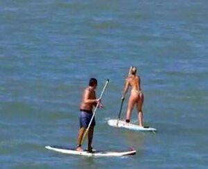 Lovable butt in g-string swimsuit on surfboard.